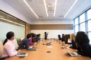 people on conference table looking at talking woman