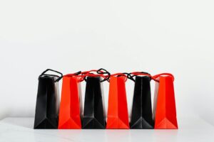 Five red and black shopping bags aligned neatly with copyspace on white background.
