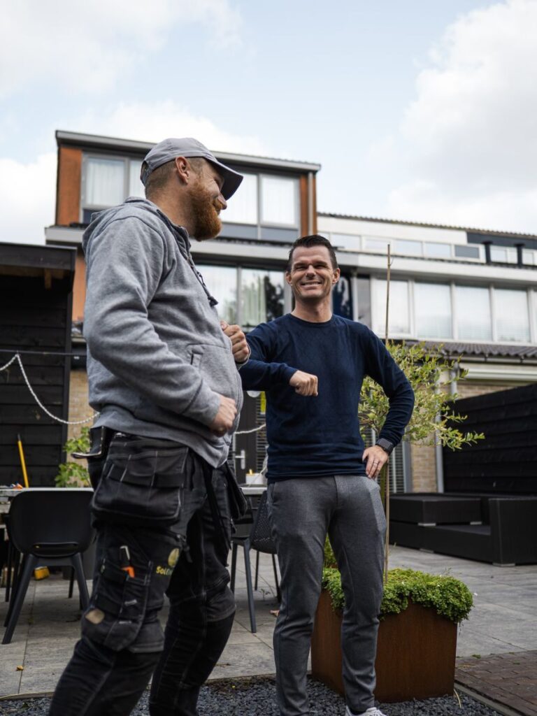 Two men share an elbow bump outdoors, showcasing camaraderie and friendliness.